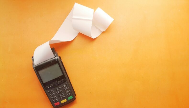 a credit card reader with a long white paper roll