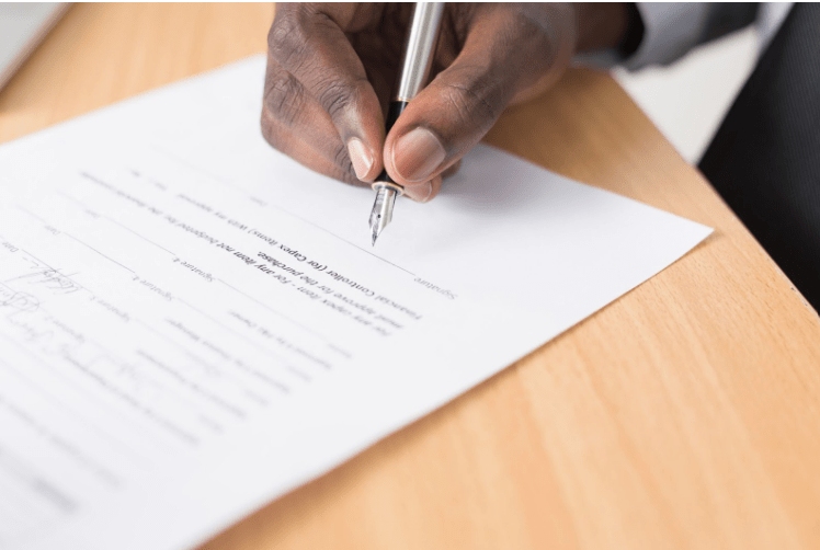 a male hand holding a fountain pen and signing a document